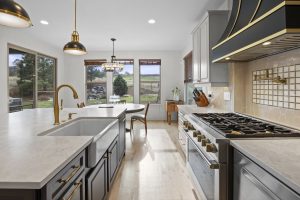 Luxury chef’s kitchen in a Pradera home featuring a large quartz island, professional-style appliances, brass fixtures, custom cabinetry, and views of the outdoor living area.