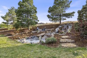 Custom backyard water feature at a Pradera luxury home in Parker, Colorado, surrounded by natural stone, mature landscaping, and peaceful outdoor living space.